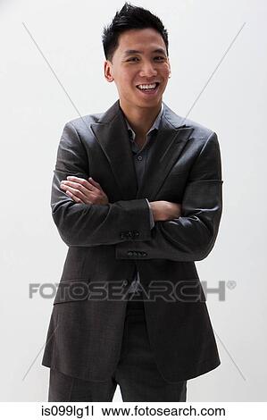Stock Image - Young Asian businessman smiling, studio shot. Fotosearch
