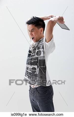 Young Asian man about to break digital tablet, studio shot View Large Photo Image Stock Image - Young Asian man about to break digital tablet, studio shot. Fotosearch