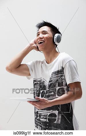 Young Asian man using digital tablet with headphones, studio shot View Large Photo Image Stock Image - Young Asian man using digital tablet with headphones, studio shot. Fotosearch