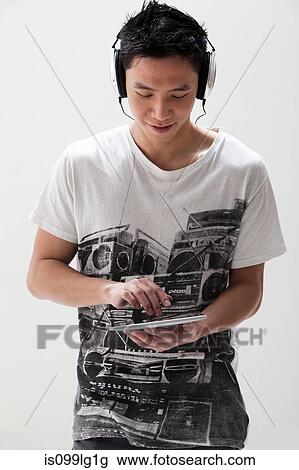 Young Asian man using digital tablet with headphones, studio shot View Large Photo Image Stock Image - Young Asian man using digital tablet with headphones, studio shot. Fotosearch