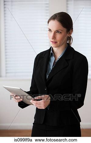 Stock Image - Young businesswoman using digital tablet, studio shot. Fotosearch