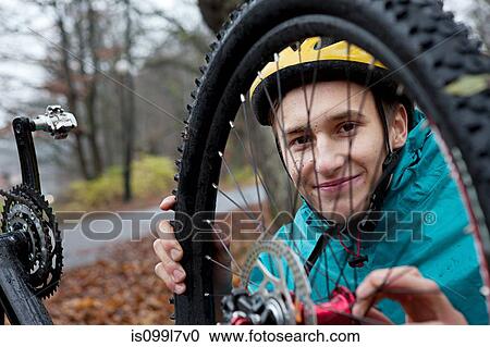 Young man fixing bicycle wheel in forest View Large Photo Image Stock Image - Young man fixing bicycle wheel in forest. Fotosearch