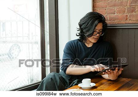 Young man using digital tablet in cafe View Large Photo Image Stock Photo - Young man using digital tablet in cafe. Fotosearch