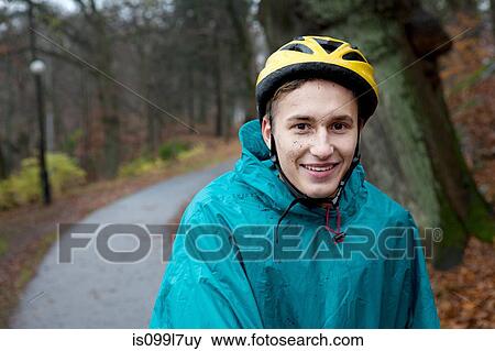 Stock Photo - Young man wearing cycling helmet on forest path. Fotosearch