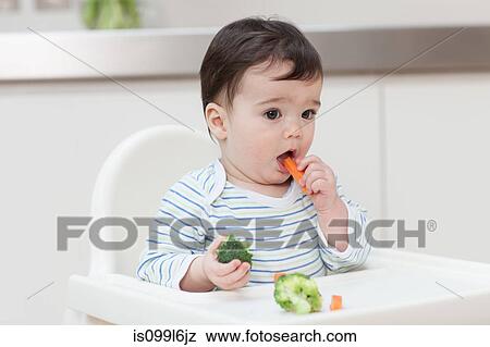 Stock Photo - Baby boy eating healthy vegetables. Fotosearch