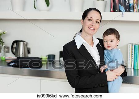 Stock Image - Businesswoman holding baby son. Fotosearch