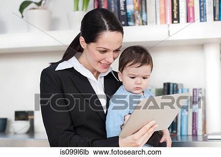 Businesswoman mother and baby looking at digital tablet View Large Photo Image Stock Image - Businesswoman mother and baby looking at digital tablet. Fotosearch