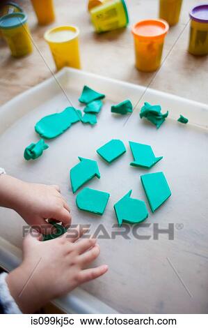 Stock Image - Child making recycling symbol from play clay. Fotosearch