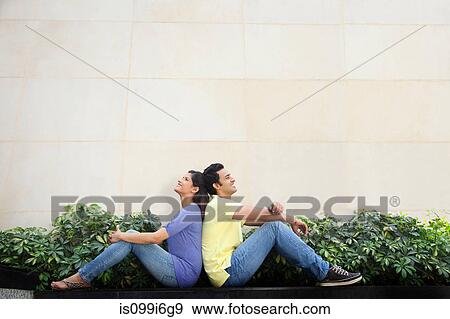 Couple sitting back to back View Large Photo Image Stock Photo - Couple sitting back to back. Fotosearch