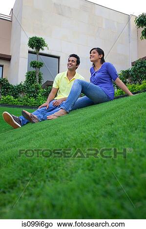 Couple sitting on a lawn View Large Photo Image Picture - Couple sitting on a lawn. Fotosearch