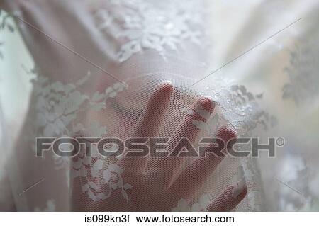 Stock Image - Hand of woman behind lace curtain. Fotosearch