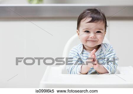 Stock Photography - Happy baby in high chair. Fotosearch