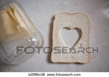 Stock Photo - Heart shaped cut out from slice of bread. Fotosearch
