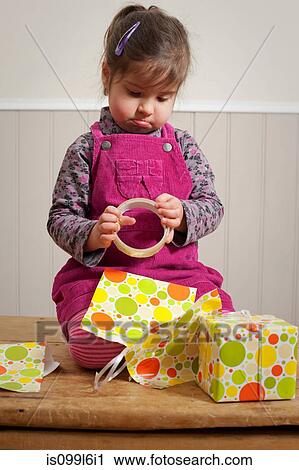 Little girl frowning as she wraps a gift View Large Photo Image Stock Image - Little girl frowning as she wraps a gift. Fotosearch
