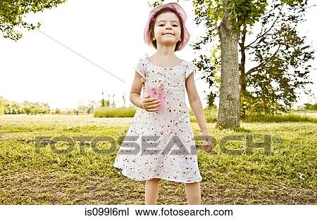 Little girl in park, holding cup of flowers View Large Photo Image Stock Image - Little girl in park, holding cup of flowers. Fotosearch