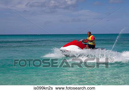Man jet skiing in Caribbean sea, Grand Cayman, Cayman Islands View Large Photo Image Stock Photograph - Man jet skiing in Caribbean sea, Grand Cayman, Cayman Islands. Fotosearch