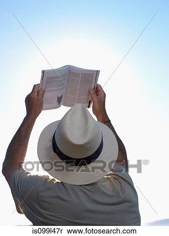Stock Photography - Man reading book against sunny sky. Fotosearch