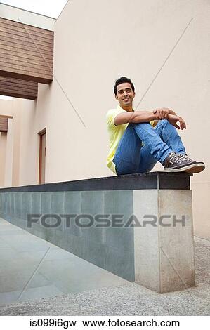 Stock Photo - Man sitting on a wall. Fotosearch
