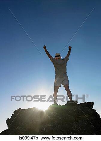 Man standing on top of rock with arms raised View Large Photo Image Stock Photography - Man standing on top of rock with arms raised. Fotosearch