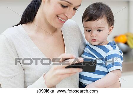 Mother and baby son looking at smartphone View Large Photo Image Stock Image - Mother and baby son looking at smartphone. Fotosearch