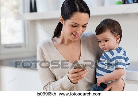 Mother and baby son looking at smartphone View Large Photo Image Stock Image - Mother and baby son looking at smartphone. Fotosearch