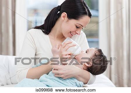 Stock Photo - Mother bottle feeding baby boy. Fotosearch