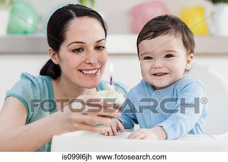 Mother giving birthday cupcake to baby son View Large Photo Image Stock Image - Mother giving birthday cupcake to baby son. Fotosearch