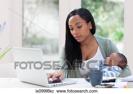 Mother holding baby son and using laptop View Large Photo Image Stock Image - Mother holding baby son and using laptop. Fotosearch