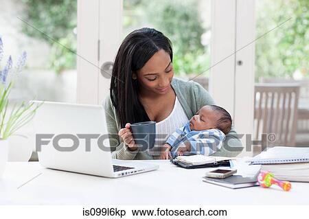 Stock Photography - Mother holding baby son, with laptop and coffee cup. Fotosearch