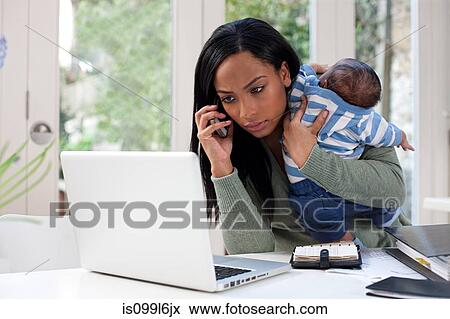 Stock Photo - Mother holding baby, using cellphone and laptop. Fotosearch