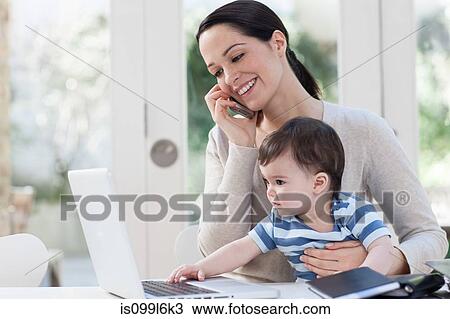 Mother on cellphone and baby looking at laptop View Large Photo Image Stock Image - Mother on cellphone and baby looking at laptop. Fotosearch