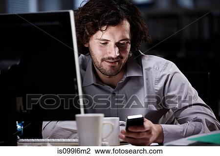 Office worker looking at cellphone in dark office View Large Photo Image Stock Image - Office worker looking at cellphone in dark office. Fotosearch