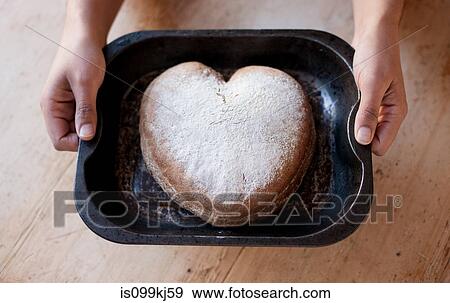 Stock Photo - Person holding a tray with heart shaped cake. Fotosearch