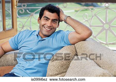 Portrait of a man sitting on a sofa View Large Photo Image Stock Photo - Portrait of a man sitting on a sofa. Fotosearch