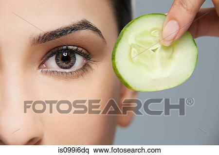 Woman with a cucumber next to her eye View Large Photo Image Stock Photography - Woman with a cucumber next to her eye. Fotosearch