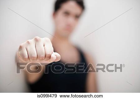 Young man holding fist out towards camera, focus on foreground View Large Photo Image Stock Photo - Young man holding fist out towards camera, focus on foreground. Fotosearch