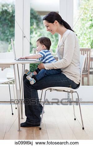 Young woman and baby son using laptop View Large Photo Image Stock Image - Young woman and baby son using laptop. Fotosearch