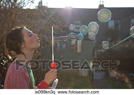 Young woman blowing bubbles outdoors View Large Photo Image Stock Photography - Young woman blowing bubbles outdoors. Fotosearch