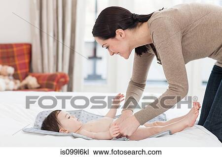 Stock Image - Young woman changing baby son. Fotosearch
