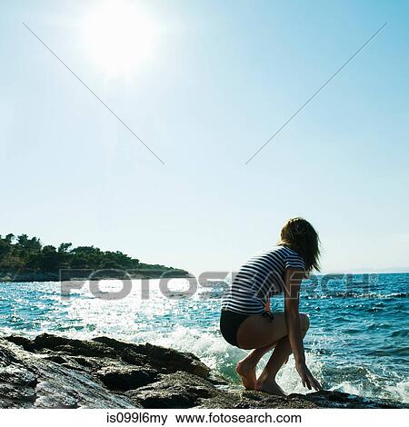 Young woman crouching by the sea View Large Photo Image Stock Photo - Young woman crouching by the sea. Fotosearch