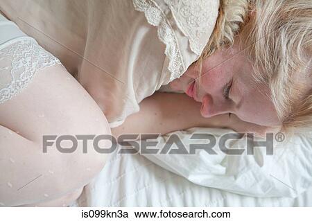 Young woman lying on bed View Large Photo Image Stock Image - Young woman lying on bed. Fotosearch