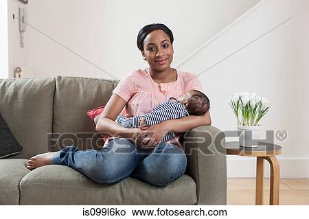 Picture - Young woman on sofa with baby son. Fotosearch