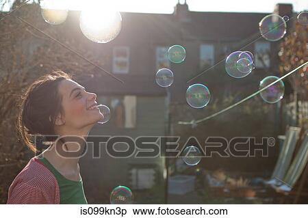 Young woman outdoors with bubbles floating in air View Large Photo Image Stock Photography - Young woman outdoors with bubbles floating in air. Fotosearch