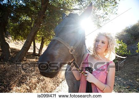 Stock Image - Young woman with horse in sunlight. Fotosearch