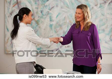 Art dealer shaking hands with young woman at desk in gallery View Large Photo Image Stock Image - Art dealer shaking hands with young woman at desk in gallery. Fotosearch