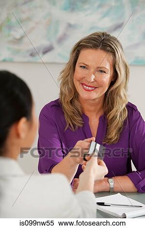 Art dealer taking credit card from young woman at desk in gallery View Large Photo Image Stock Photography - Art dealer taking credit card from young woman at desk in gallery. Fotosearch