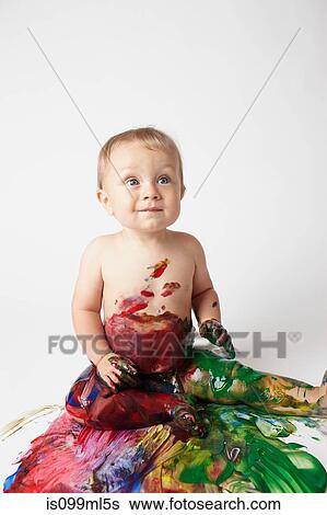 Stock Photograph - Baby covered in messy paint. Fotosearch