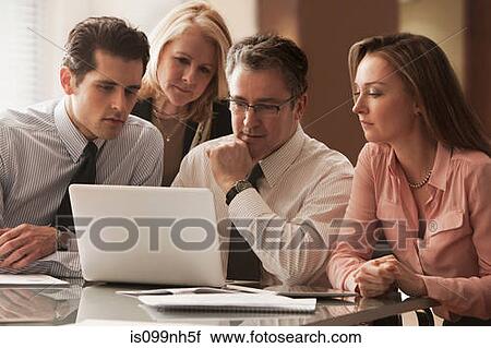 Stock Image - Business colleagues working on laptop on desk. Fotosearch