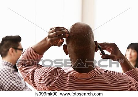 Stock Image - Businessman on phone with hand on head, rear view. Fotosearch