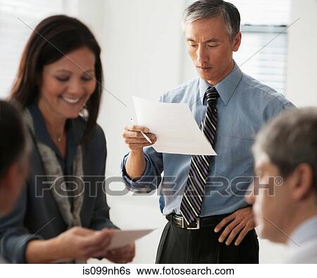 Businessman reading document in office with colleagues View Large Photo Image Stock Photograph - Businessman reading document in office with colleagues. Fotosearch